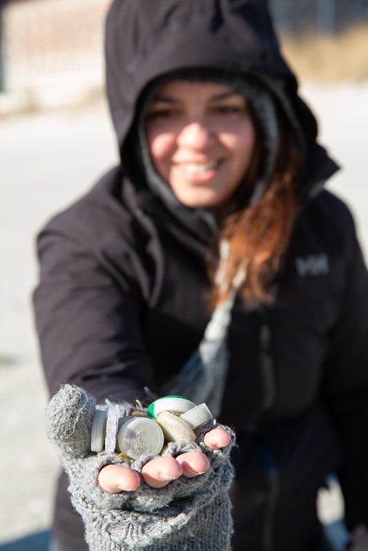 Surfrider Chapter Cleanup Volunteer Holding a Handful of Plastic Bottle Caps